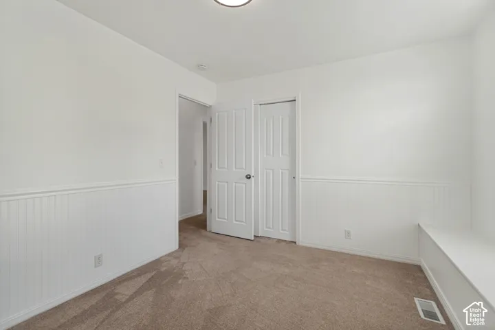 Neutral wall paint with wainscoting detail, carpet flooring, and a built-in bench