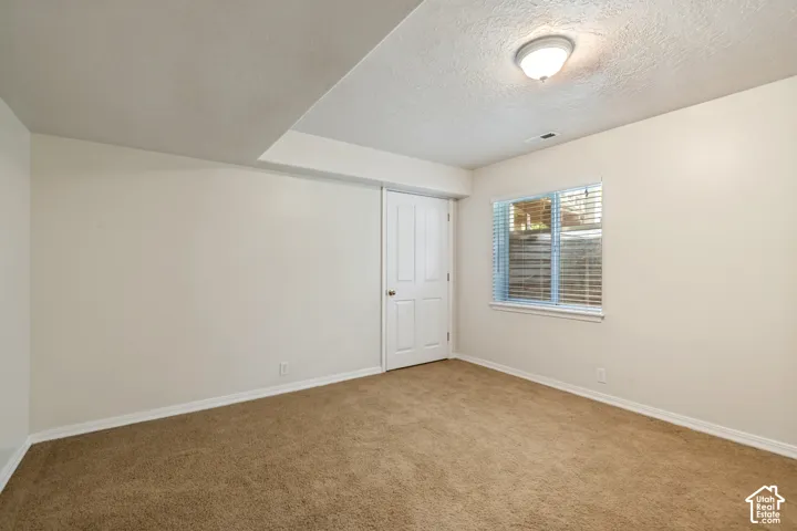 Brown carpet flooring, neutral painted walls, white trim, window with blinds, and white paneled doors
