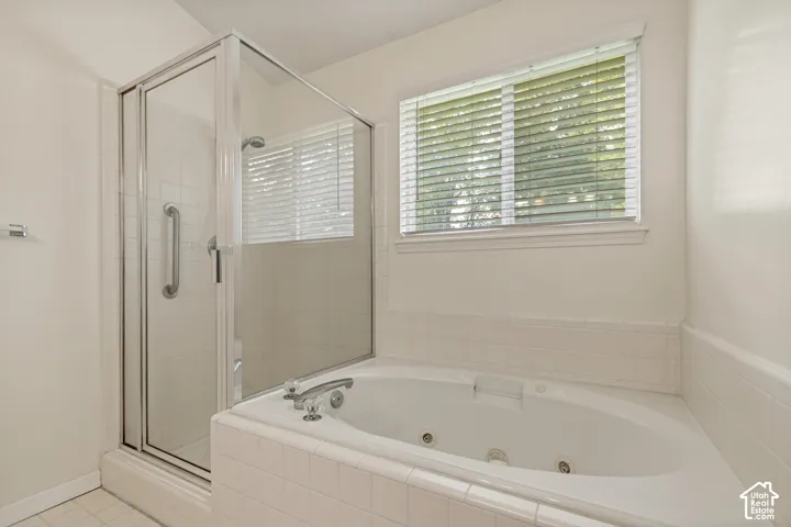 Enclosed shower with glass door, deep soaking tub, and a window with horizontal blinds