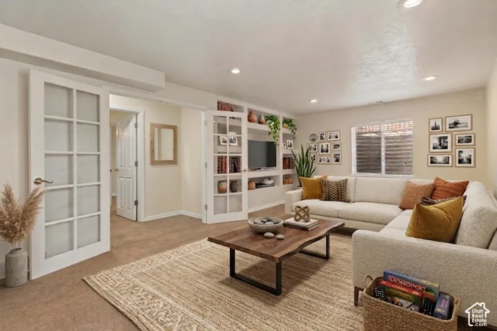 Recessed lighting, wood-finish coffee table, built-in shelving, carpet flooring, and French doors