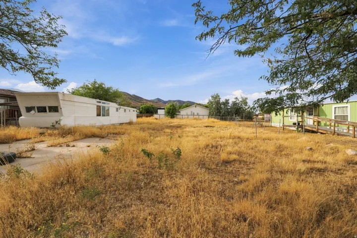 Expansive lot featuring a vibrant green structure with a wooden ramp, a white structure, and a concrete pad