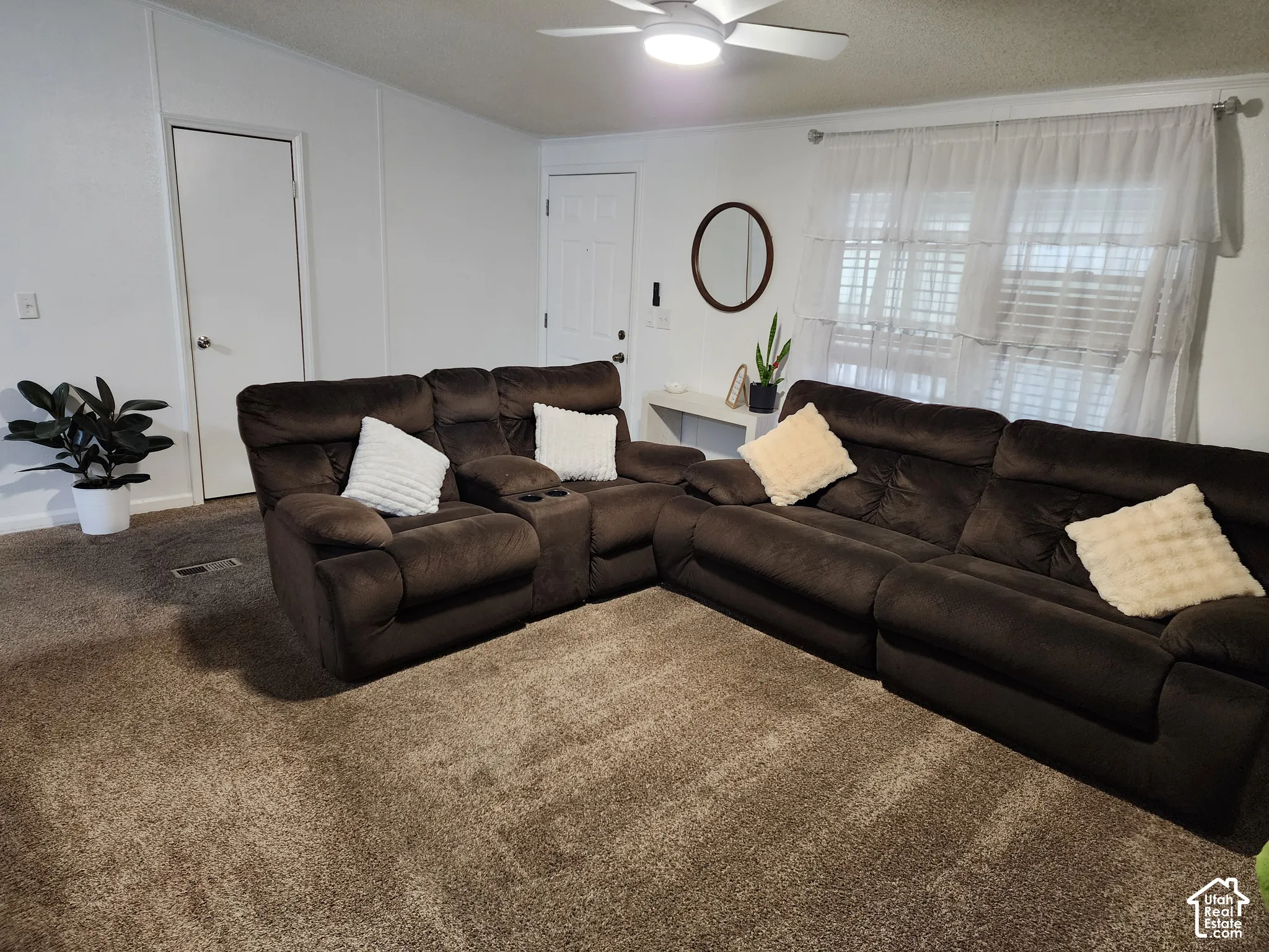 Neutral-toned wall-to-wall carpeting, ceiling fan with integrated lighting, and tiered window treatments