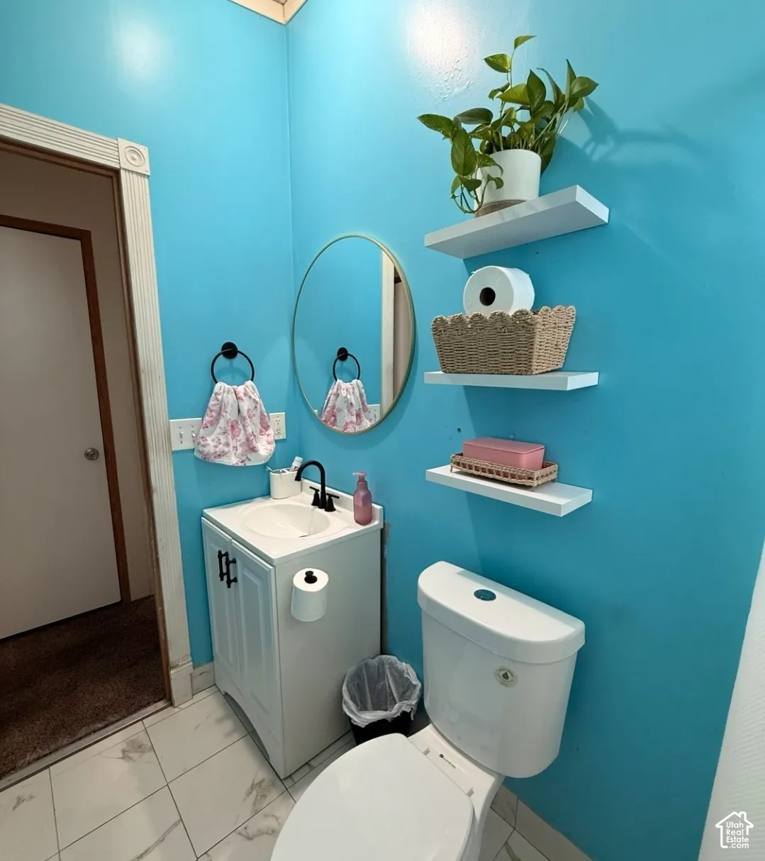 White vanity with a single basin sink, matte black faucet, and a round wall mirror