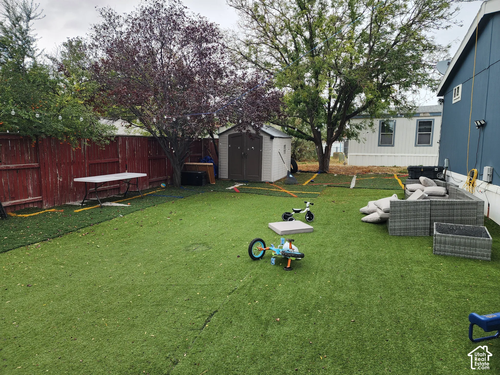 Private backyard featuring artificial turf, a wood fence enclosure, and an exterior storage shed