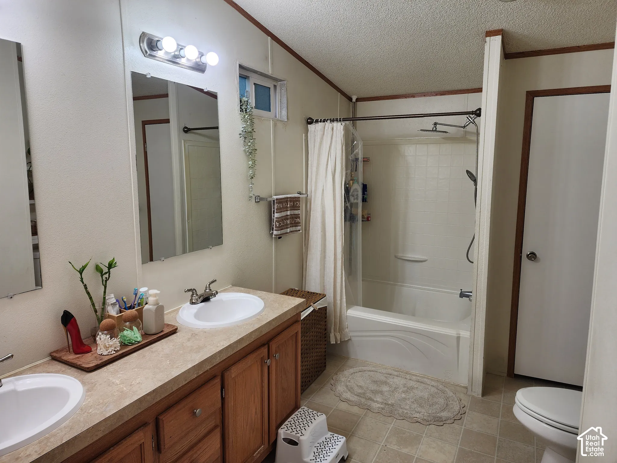 Bathroom featuring a dual-sink vanity with wood-finish cabinetry, countertop with integrated basins, and a combination tub and shower with a wall-mounted handheld sprayer