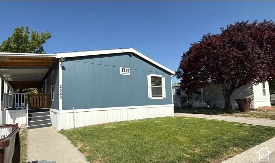 Blue exterior siding with white trim, covered porch, exterior stairs, and a grassy front yard
