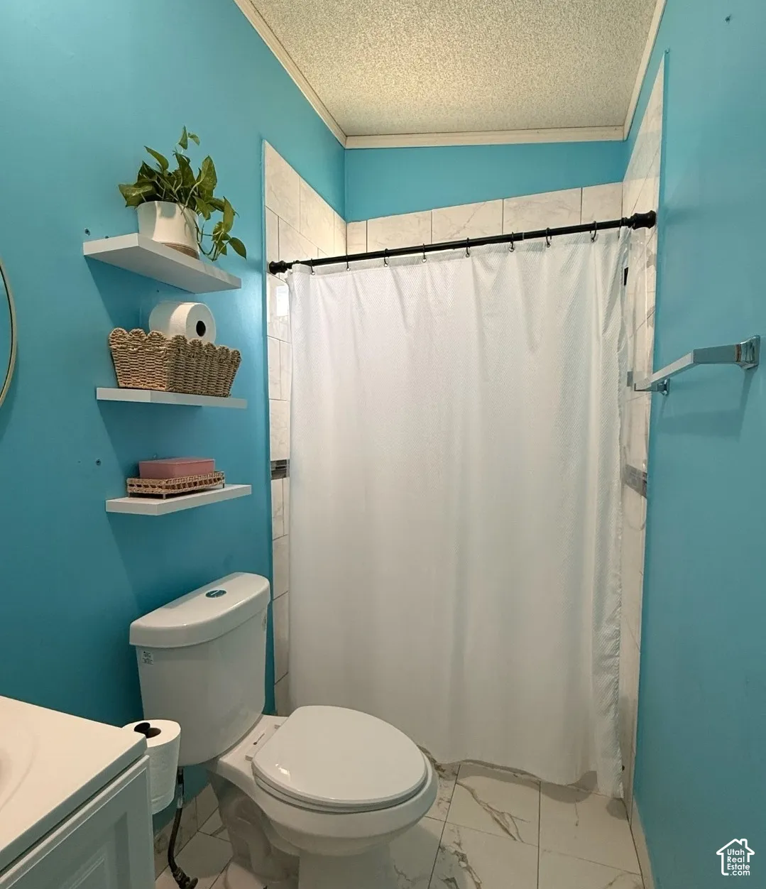 Shower with white subway tile surround, white toilet, and white floating shelves
