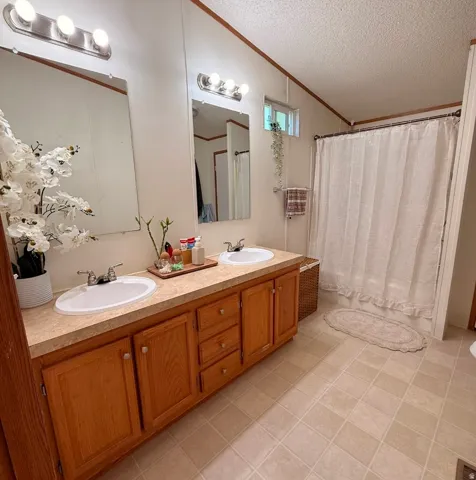 Dual vanity with white ceramic sinks, wood-finish cabinetry, and laminate countertops
