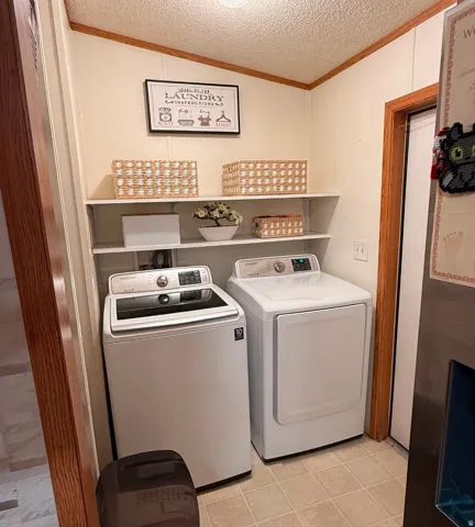 Laundry area with two white appliances, light-colored tile flooring, and white wall shelving