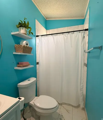 Shower with white subway tile surround, white toilet, and white floating shelves