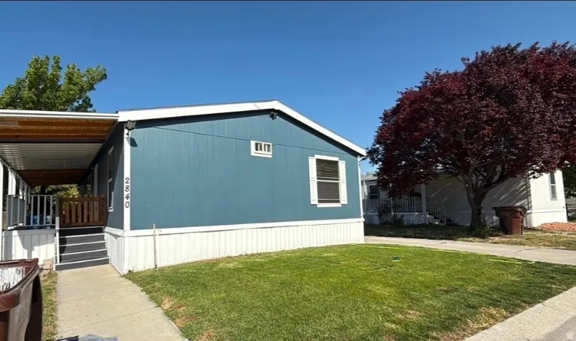 Blue exterior siding with white trim, covered porch, exterior stairs, and a grassy front yard
