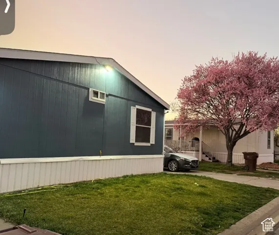 Siding exterior with vertical paneling, white window shutters, and a manicured lawn