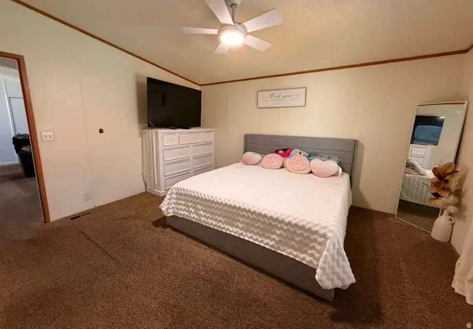 Carpeted flooring, white walls with wood trim, and a ceiling fan with integrated lighting