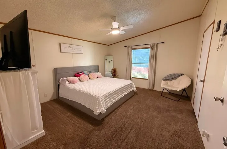Spacious room featuring carpeting, a ceiling fan, and a double-door closet