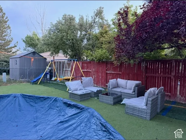 Fenced backyard with artificial turf, featuring a storage shed and mature trees