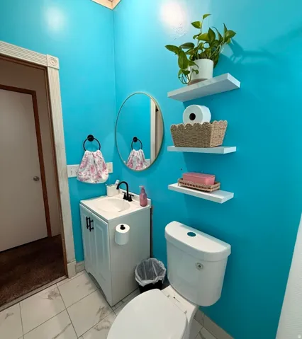 White vanity with a single basin sink, matte black faucet, and a round wall mirror