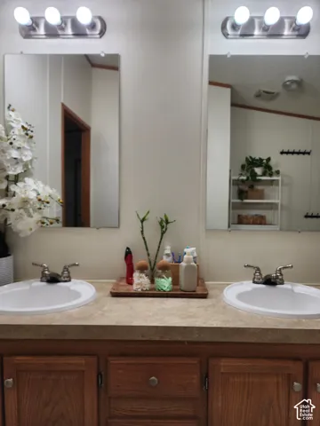 Dual-basin vanity featuring wood-finish cabinetry, a solid-surface countertop with integrated oval sinks, twin wall-mounted mirrors, and two three-light vanity fixtures