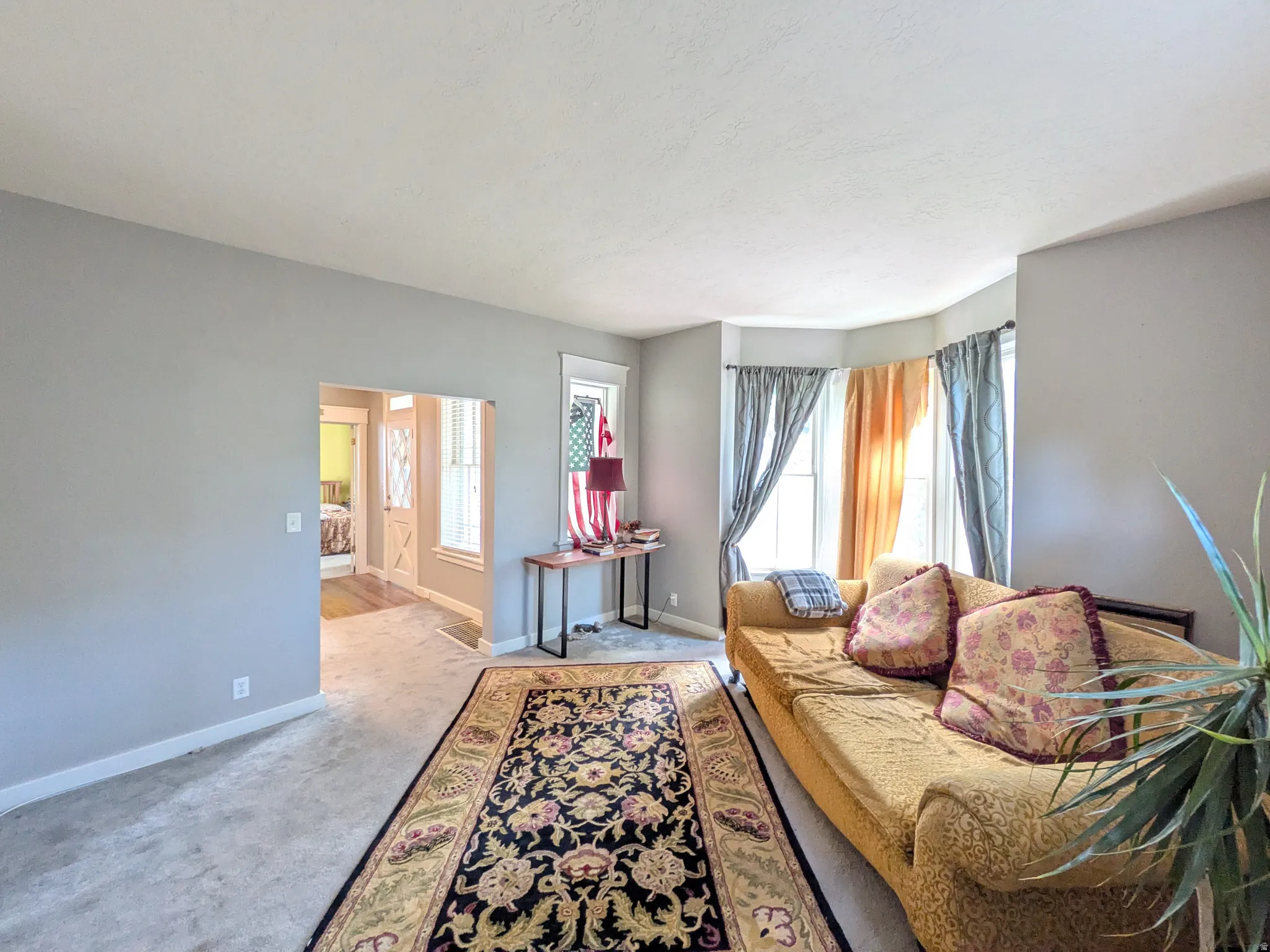 Bay window with natural light, neutral wall paint, carpeted flooring, and an open doorway