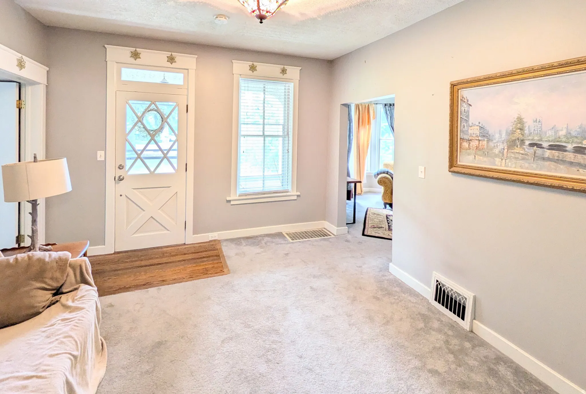 Entryway featuring a decorative transom window, white paneled door, and wood-finish flooring