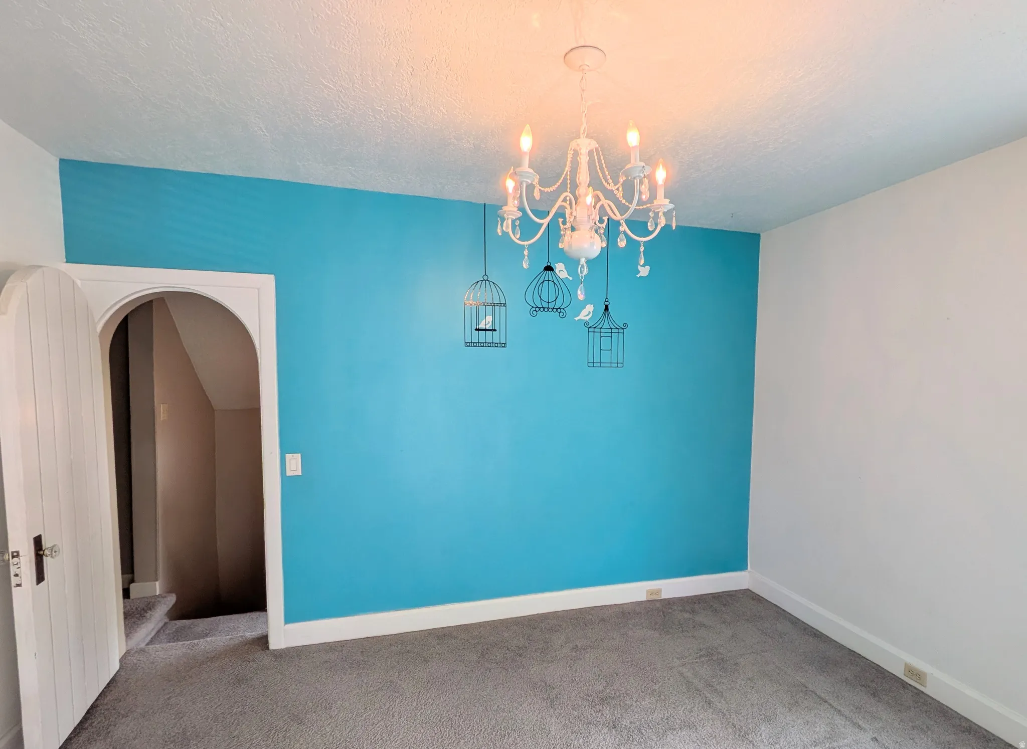 Arched doorway with a paneled door, gray carpet, and a chandelier light fixture