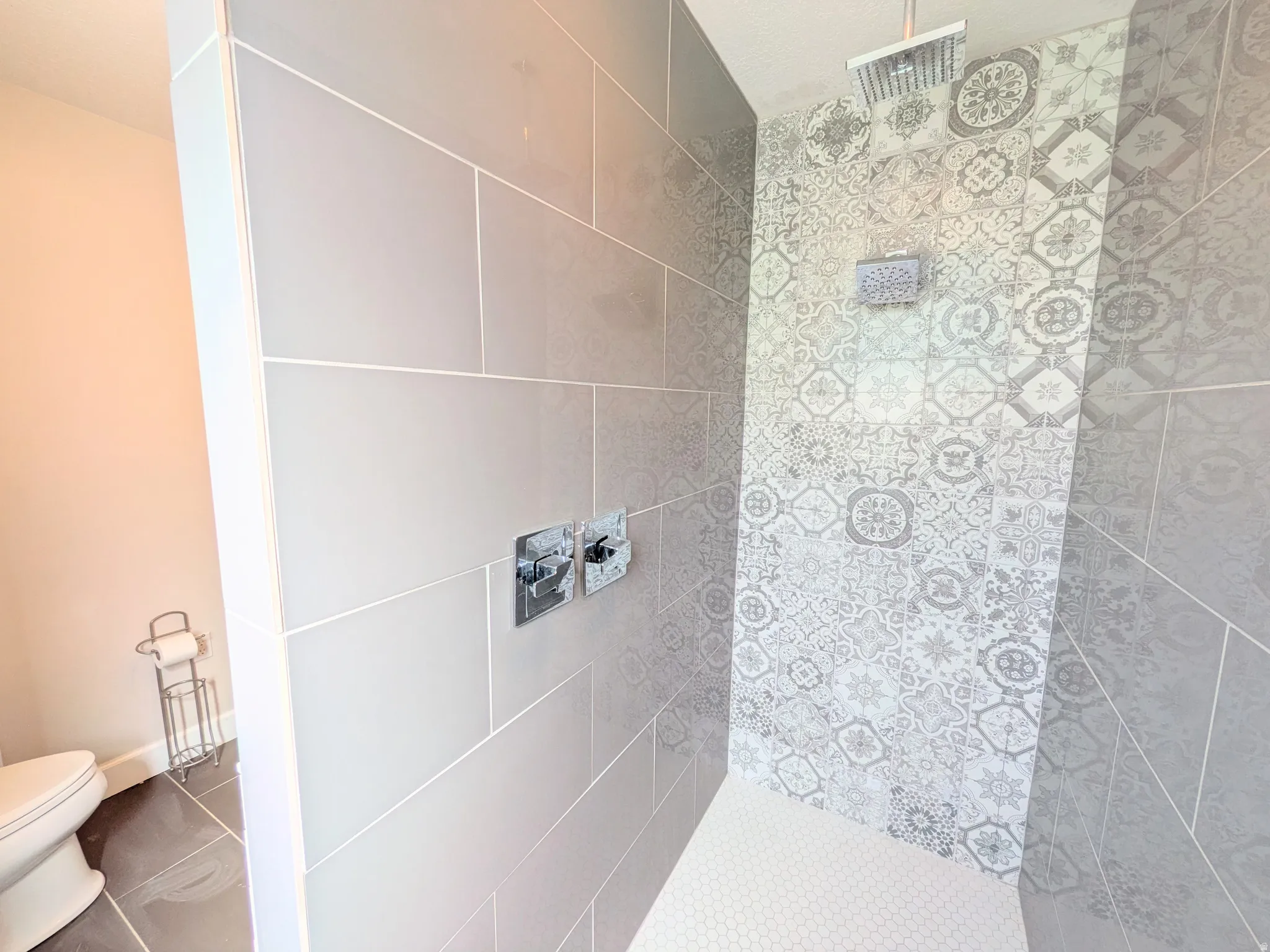 Shower with horizontal grey tile, patterned accent tile, and a square rain showerhead