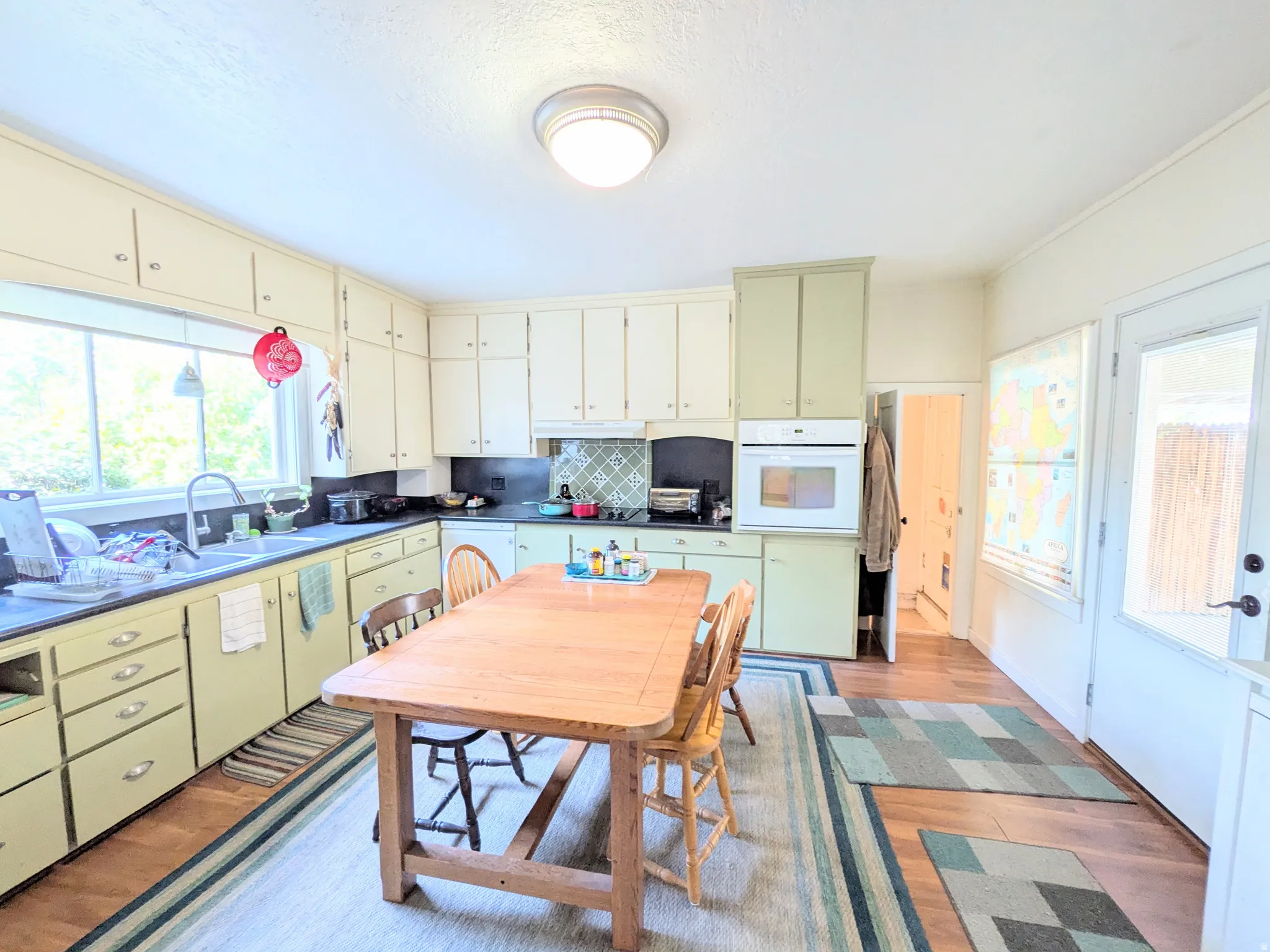 Kitchen featuring wood-finish flooring, built-in oven, overhead lighting, and ample cabinetry