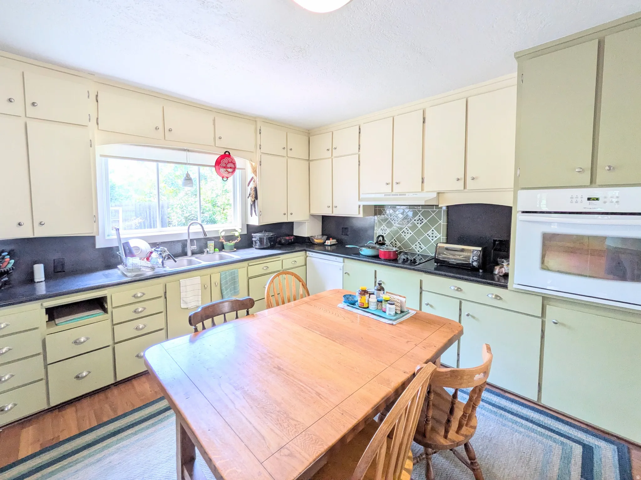 Kitchen featuring extensive cabinetry, built-in oven, integrated cooktop, and a double basin sink