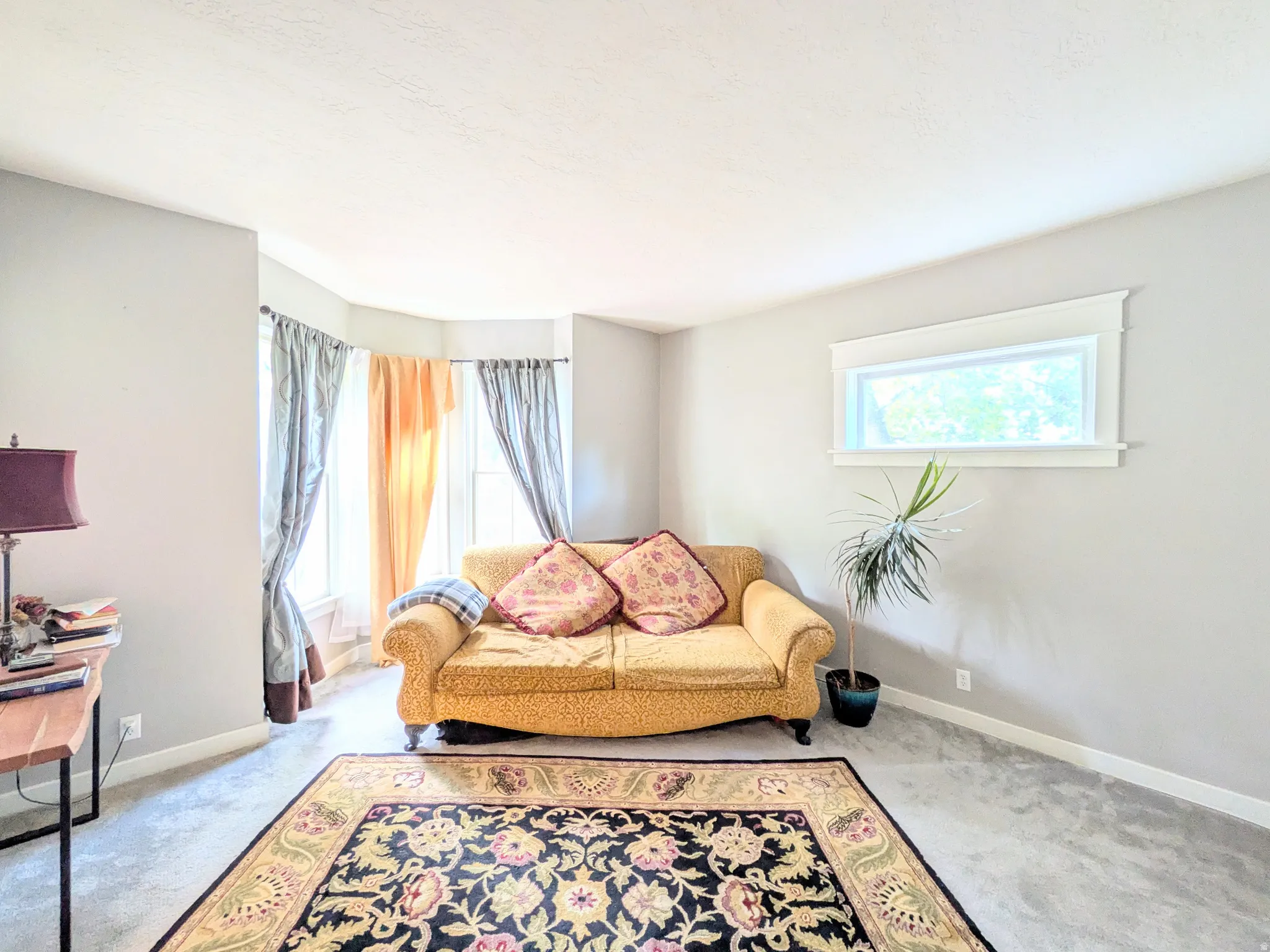 Bay window with multiple panels, carpeted flooring, and a high-set horizontal window with white trim