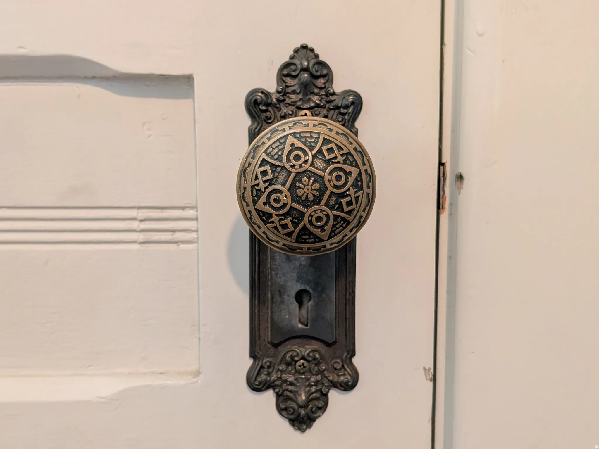 Ornate door hardware featuring a decorative brass doorknob and escutcheon plate