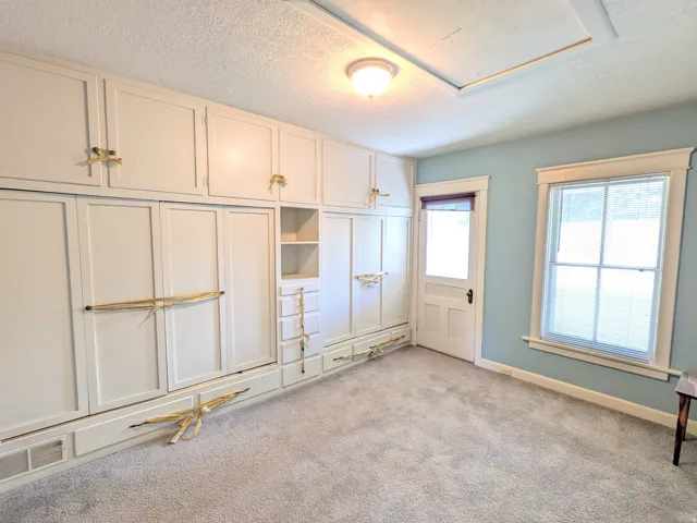 Built-in cabinetry with integrated shelving and drawers, window with white trim, paneled door, flush-mount ceiling light