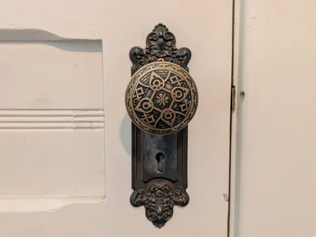 Ornate door hardware featuring a decorative brass doorknob and escutcheon plate