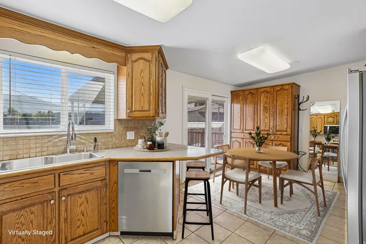 Kitchen featuring wood cabinetry, stainless steel dishwasher, tile backsplash, and a double basin sink