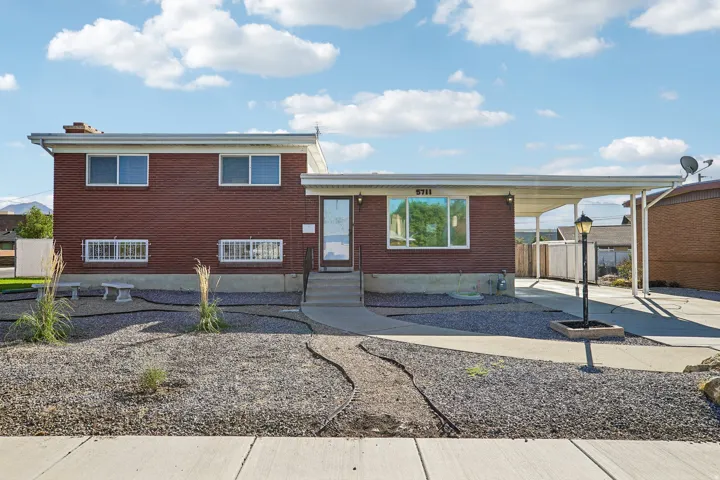 Brick exterior with an attached carport, concrete driveway, and a front walkway