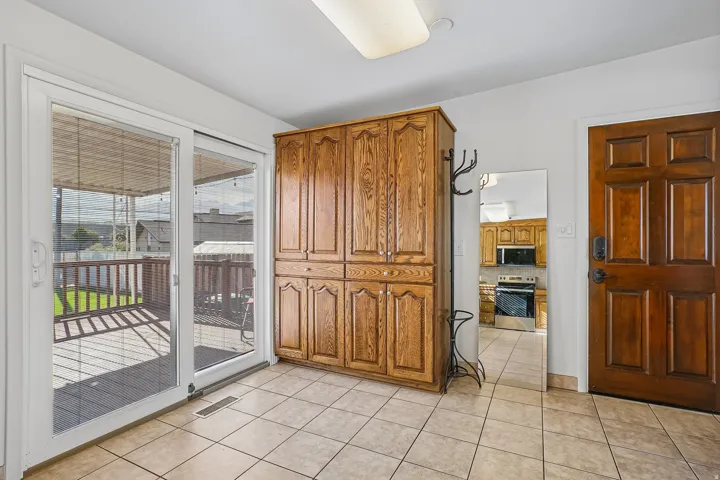Tiled flooring, wood-paneled door, built-in wooden cabinetry, and sliding glass door