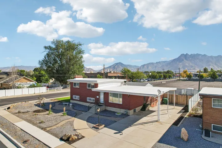 Brick exterior with white trim, covered carport, and concrete pathways