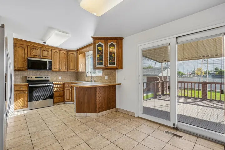 Kitchen featuring wood cabinetry, stainless steel appliances, and a tiled floor