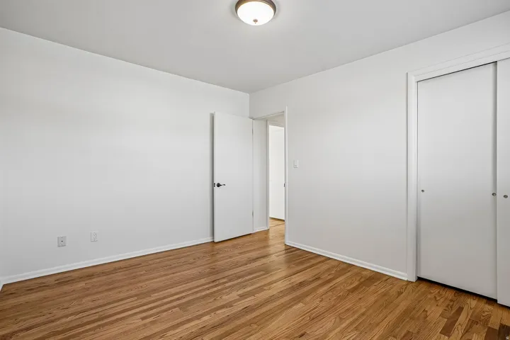 Hardwood flooring, white walls, and a ceiling-mounted light fixture