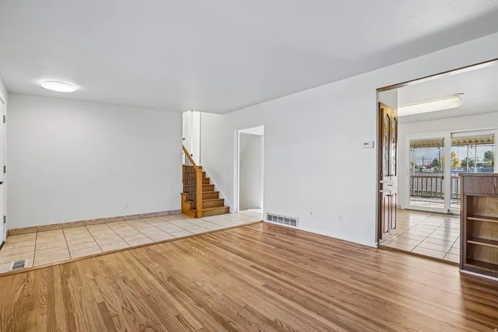 Wood-finish flooring, tiled entry, and staircase with natural wood railings