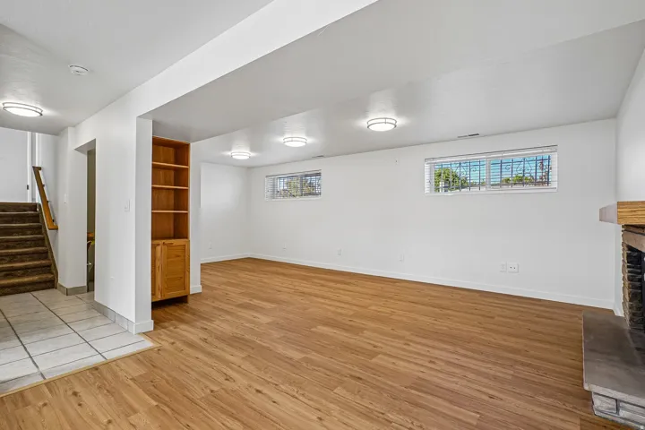 Wood-finish flooring with recessed lighting, a built-in bookshelf, and a stone fireplace