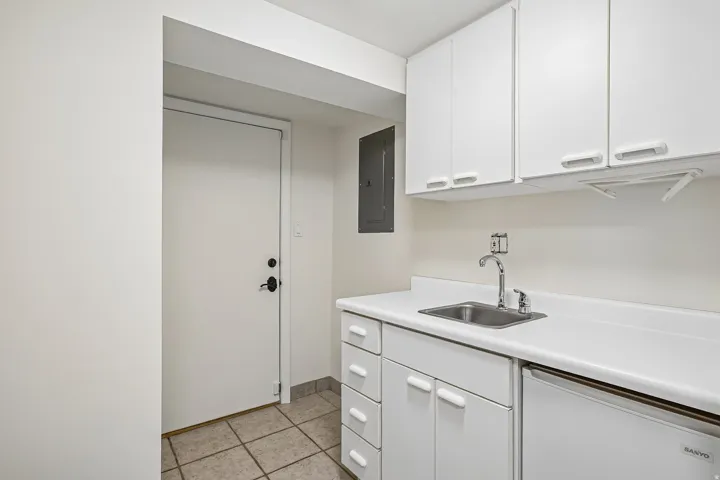 White cabinetry with integrated sink, chrome faucet, and expansive countertop