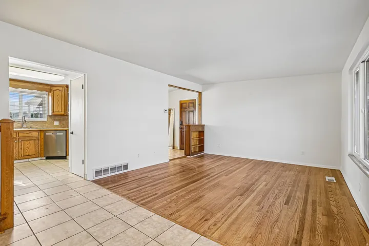 Hardwood flooring, tile flooring, white walls, and a large window