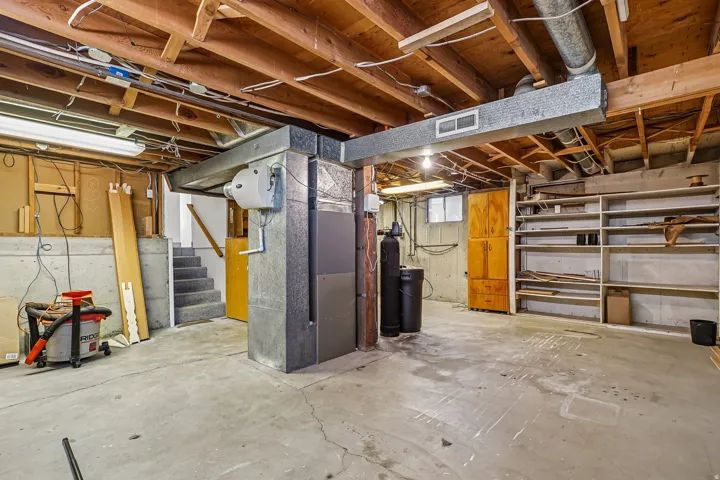 Exposed wood joists, concrete flooring, built-in shelving, and a wood-finish cabinet