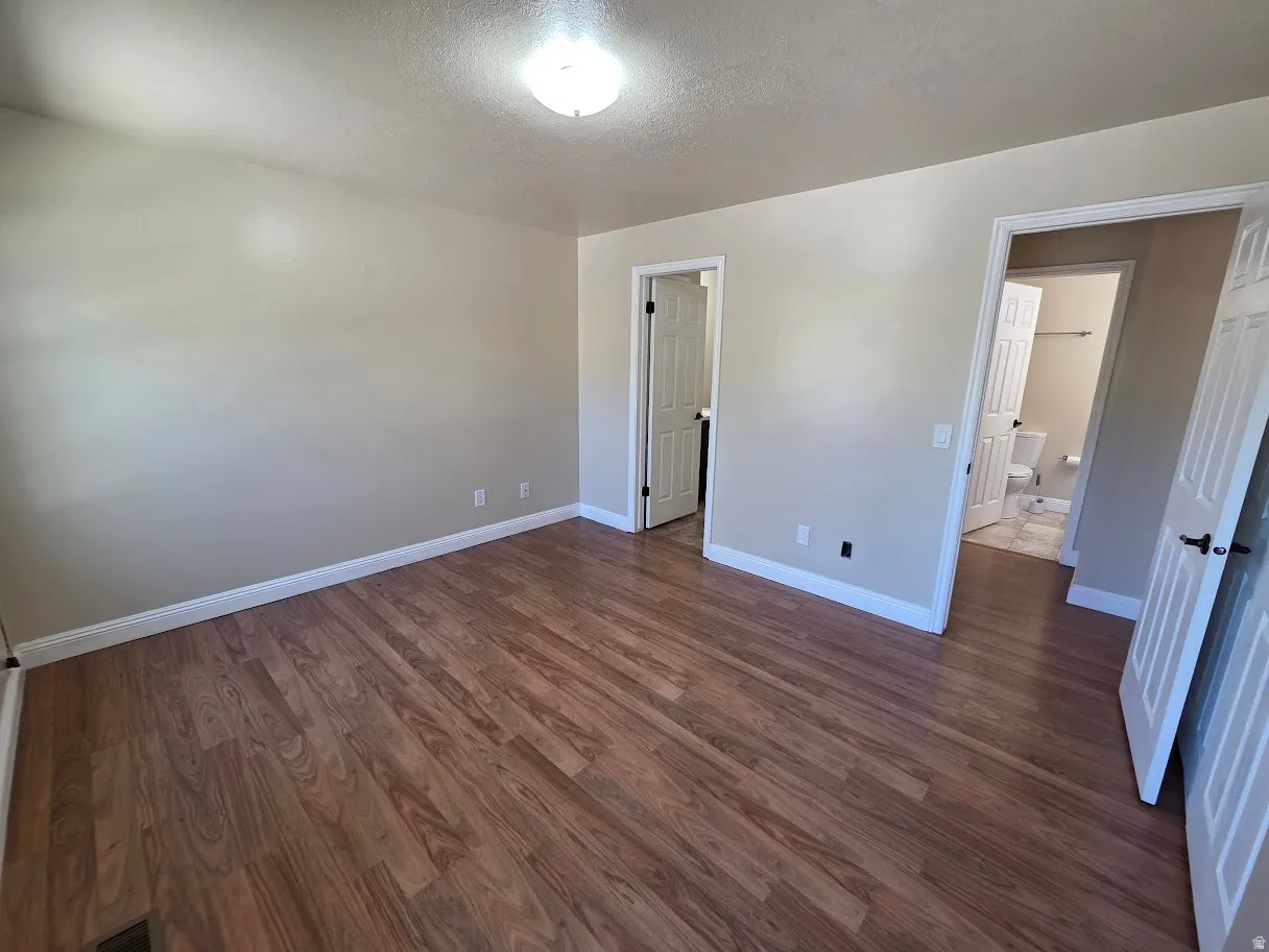 Primary Bedroom with Wood-finish flooring throughout, neutral wall tones, and white trim