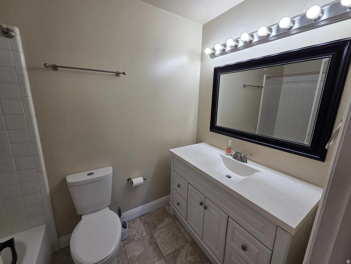 Main bathroom.  Vanity has been resurfaced since this photo.  Vanity with integrated sink, framed mirror, vanity lighting fixture, and tile flooring
