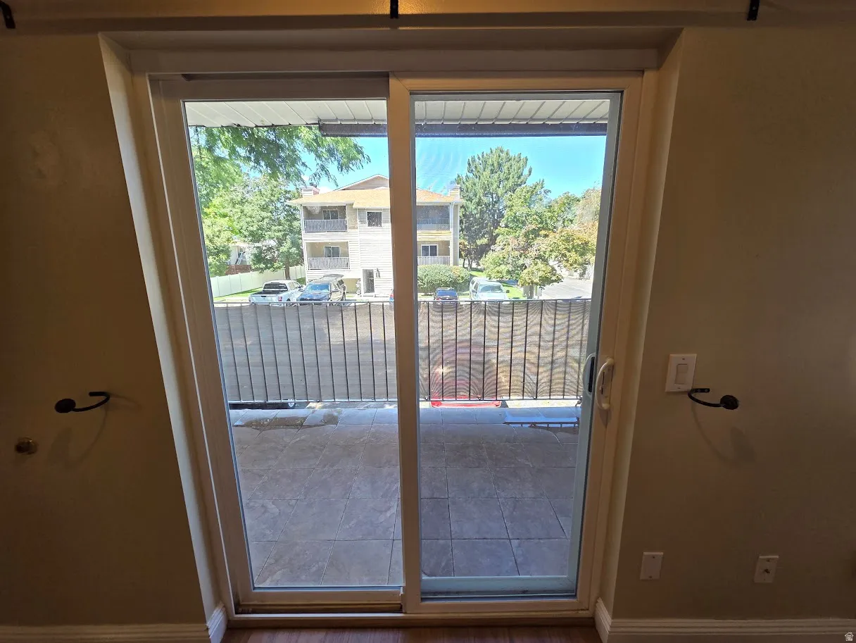 Sliding glass door leading to an outdoor balcony with tiled flooring and a metal railing