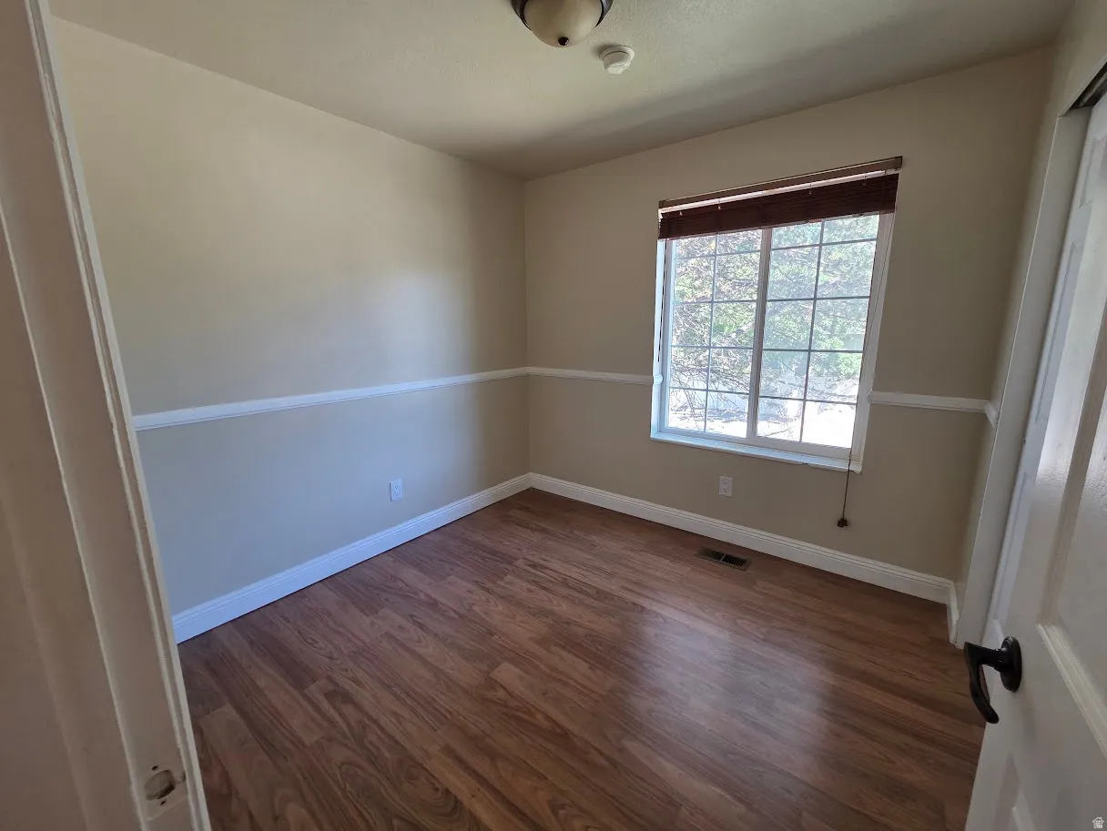 2nd Bedroom with wood-finish flooring, neutral wall tones with chair rail molding, and a window with blinds