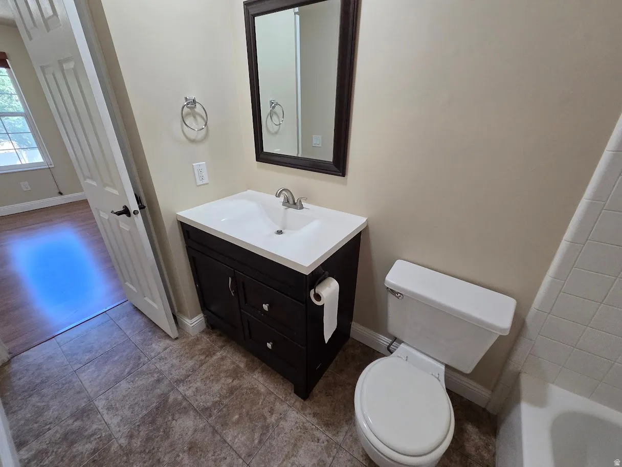 Primary Bathroom featuring a dark wood-finish vanity with a white countertop and integrated sink, a framed mirror, and tile flooring