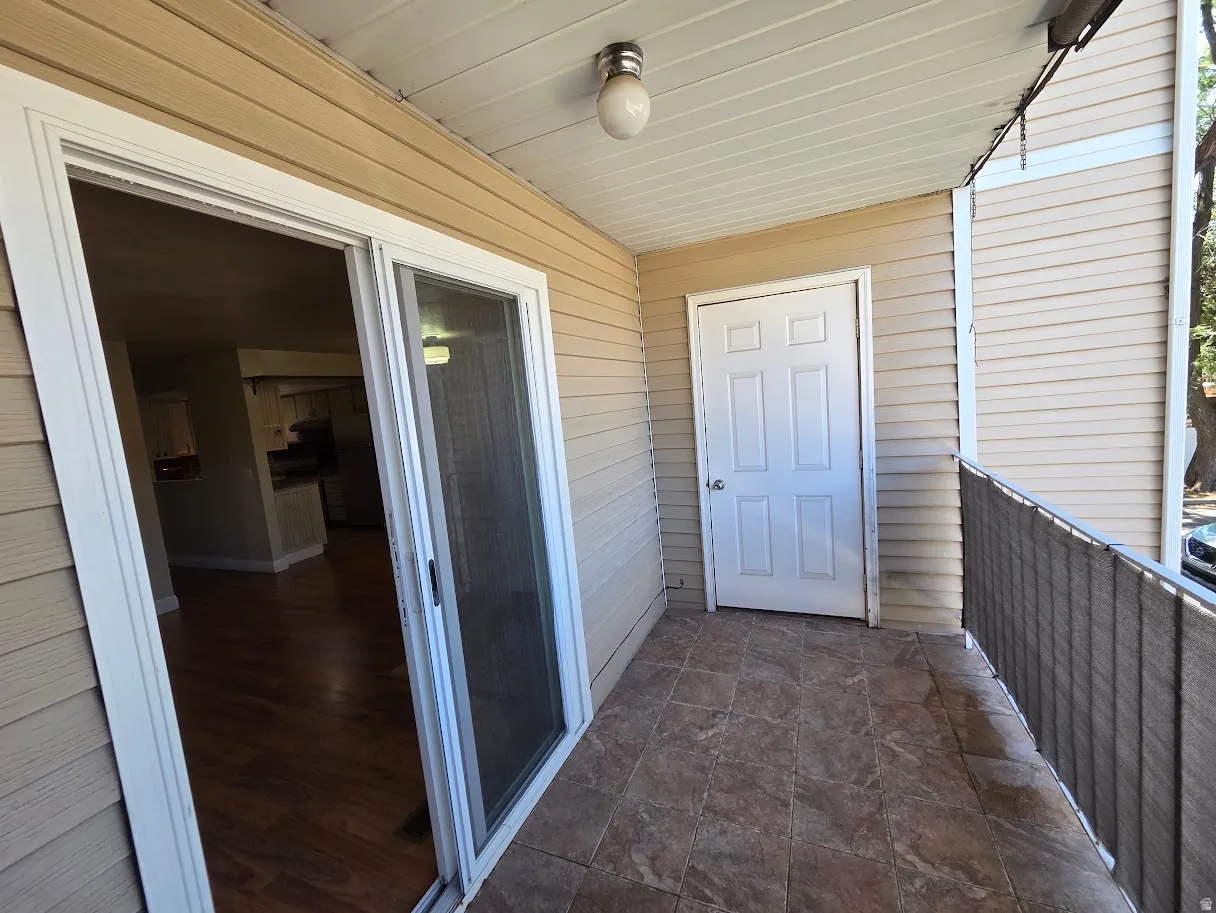 Private balcony with ceramic tile flooring, vinyl siding, and a ceiling-mounted light fixture