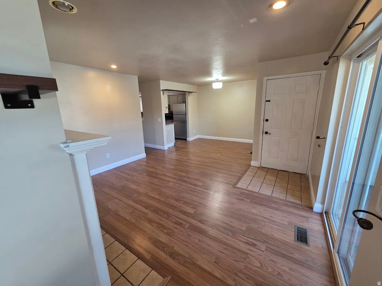 Wood-finish flooring throughout, recessed lighting, and a front entry door with side light