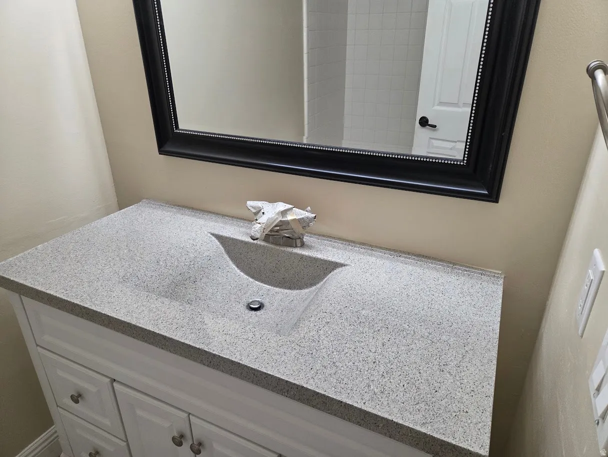 Main Bathroom Vanity after countertop was resurfaced, complemented by a framed mirror